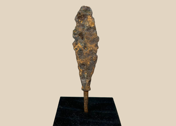 Ancient iron arrowhead relic mounted on black display base, front view.