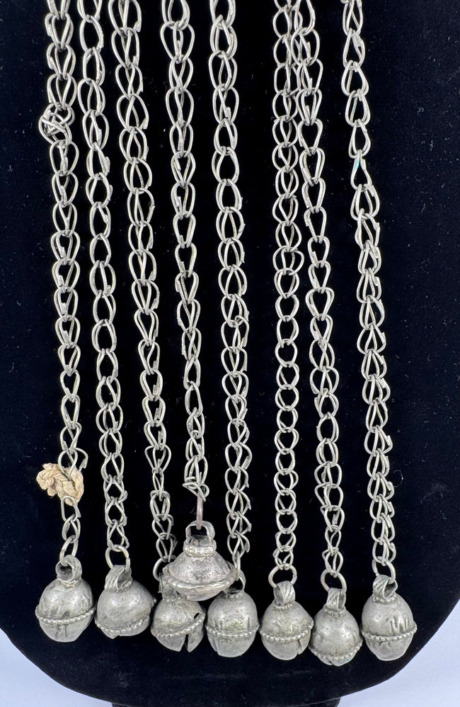 Afghan tribal pendant displaying handcrafted silver-toned metalwork, red glass accents, and ceremonial chain tassels.