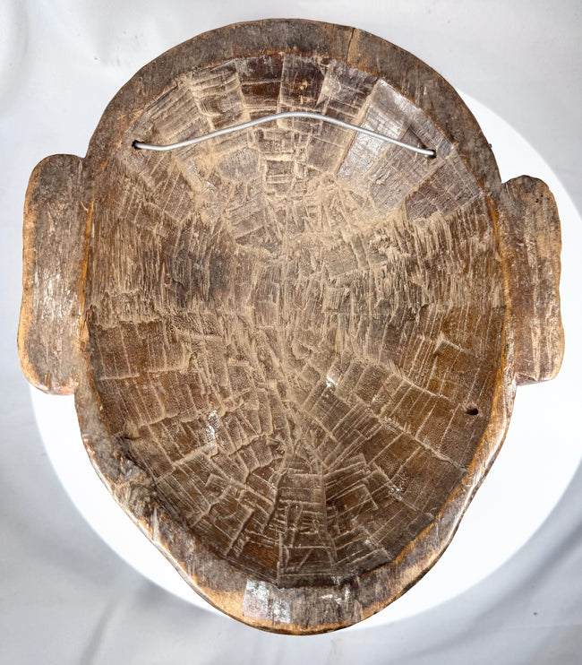 Antique African tribal mask with remnants of pigment and expressive anthropomorphic form
