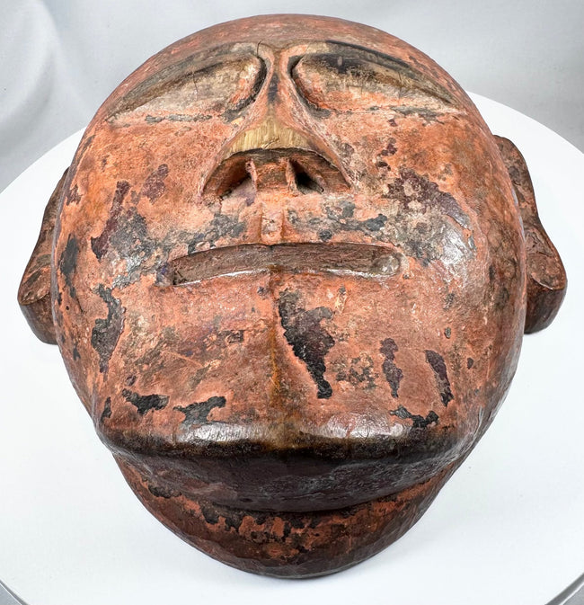 Antique African carved mask with almond-shaped eyes, hollowed reverse, and cultural significance