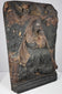 Hand-carved religious relief with deeply folded robes, recessed background and architectural framing elements