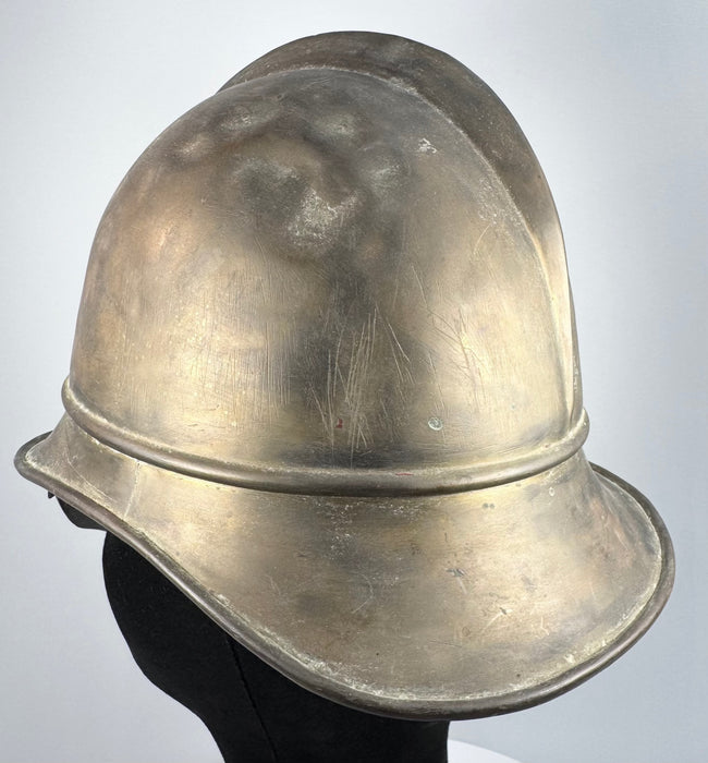 Bavarian brass firefighter helmet showing raised crown comb and aged metal patina, circa 1908–1934