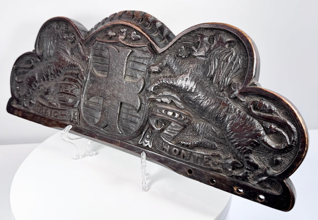 Lower edge of an antique heraldic oak cresting showing the original mounting holes and aged surface