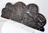 Lower edge of an antique heraldic oak cresting showing the original mounting holes and aged surface