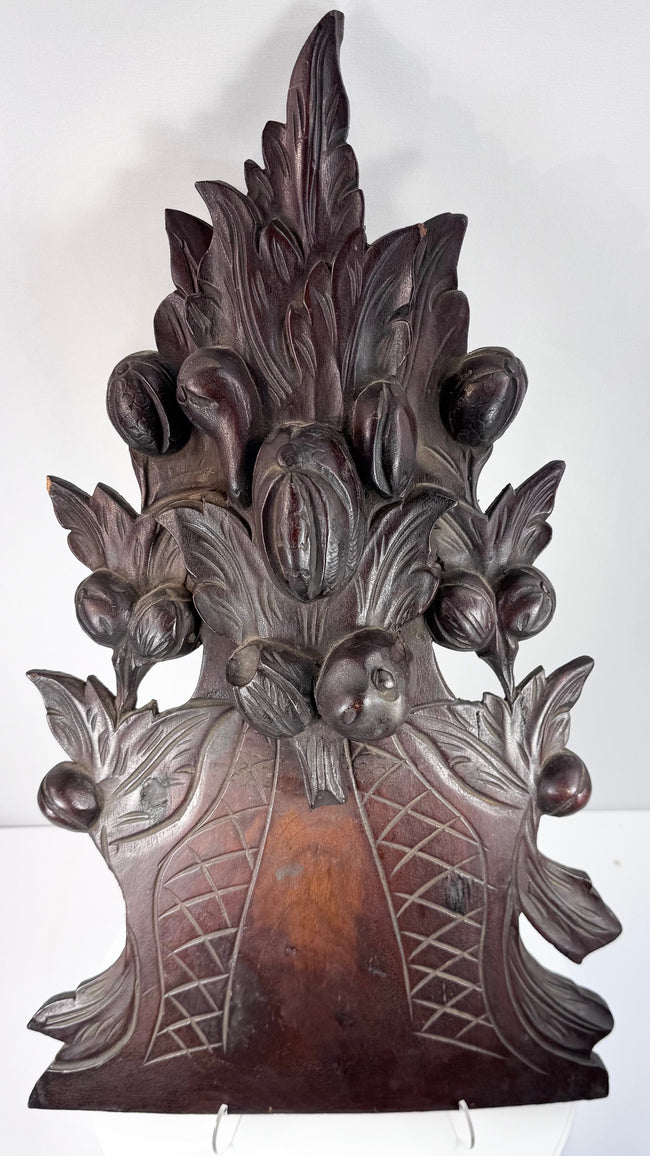 Black Forest-style carved furniture ornament showing dense botanical decoration, applied carved elements and historic surface wear