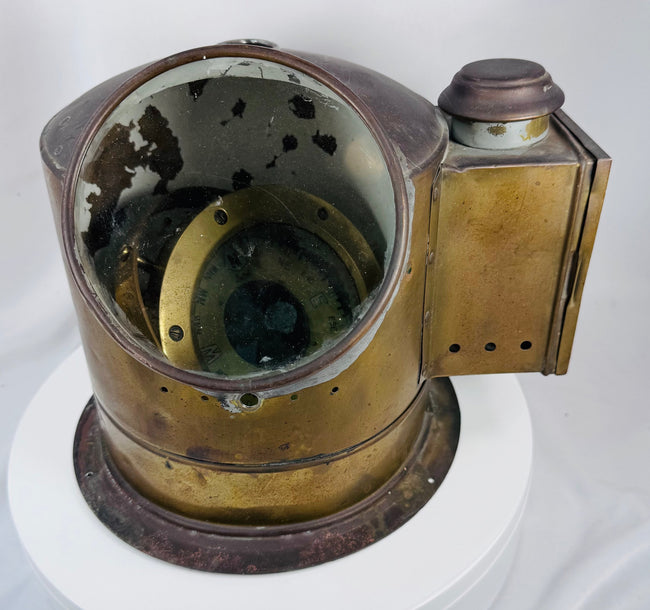 Antique nautical compass housed in a brass binnacle with circular glass viewing window