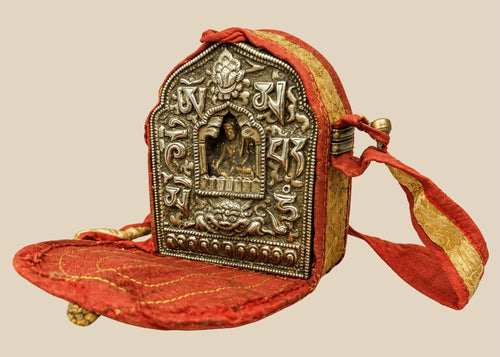 18th–19th century Tibetan Gau shrine, silvered copper alloy with repoussé seated Buddha, gilt backing plate, and original red fabric strap, portable Himalayan Buddhist amulet box
