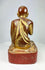 Close-up of red lacquer pedestal supporting the Burmese monk statue, showing aged texture and hand-carved form.