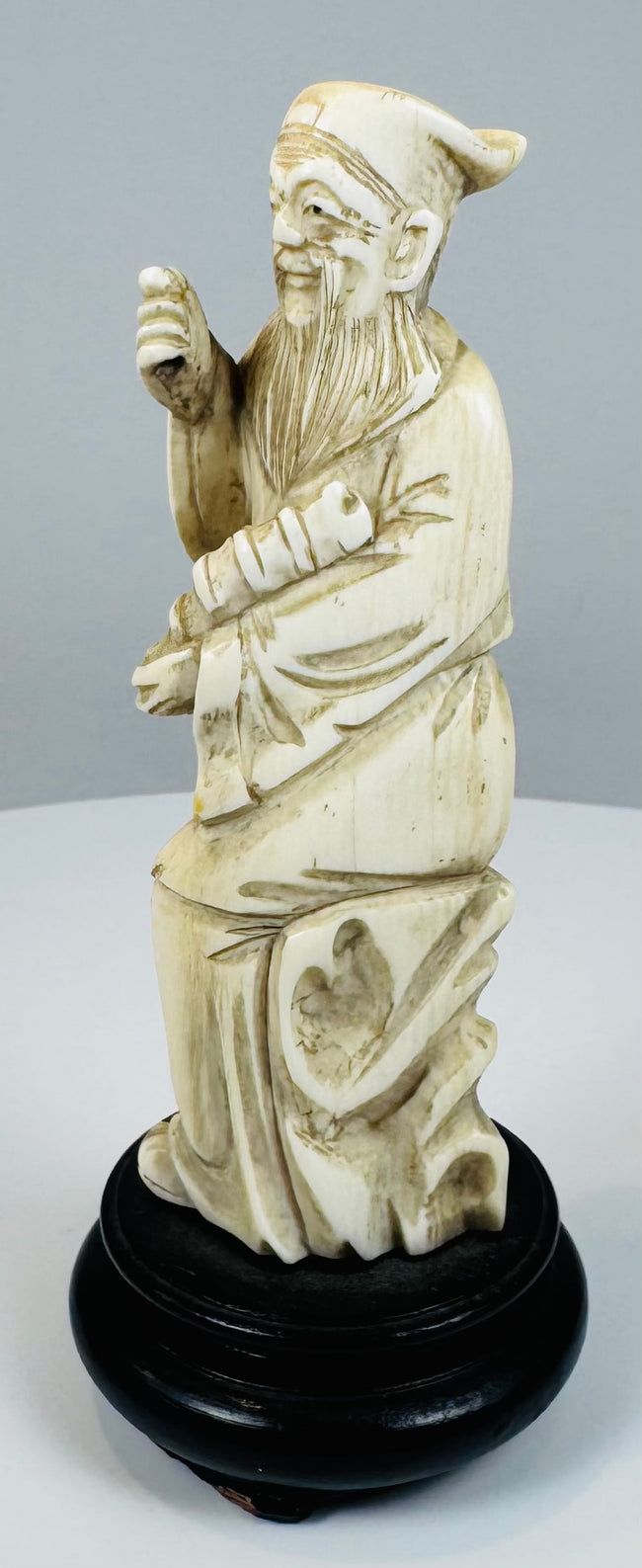 Antique Daoist immortal carving beside a stylized pierced rock-form support