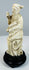 Antique Daoist immortal carving beside a stylized pierced rock-form support