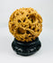 Late Qing Dynasty carved puzzle ball with layered spheres and dragon motifs on a black stand against a white background.