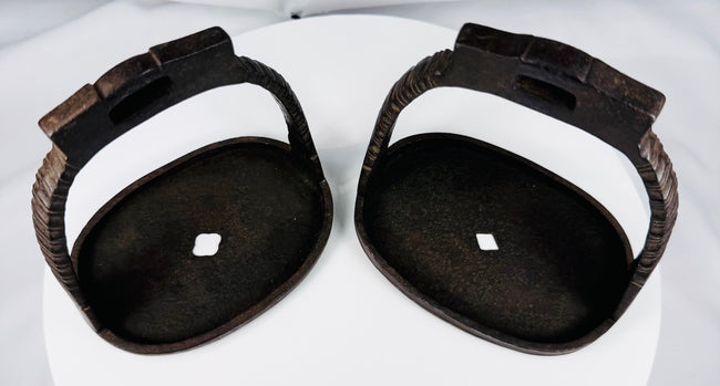 Antique Qing-era iron stirrups with rope-like motifs and dark oxidized surface