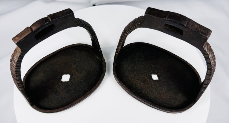 Antique Qing-era iron stirrups with rope-like motifs and dark oxidized surface
