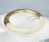 Chinese jade or hardstone bangle with chased silver mounts and aged patina