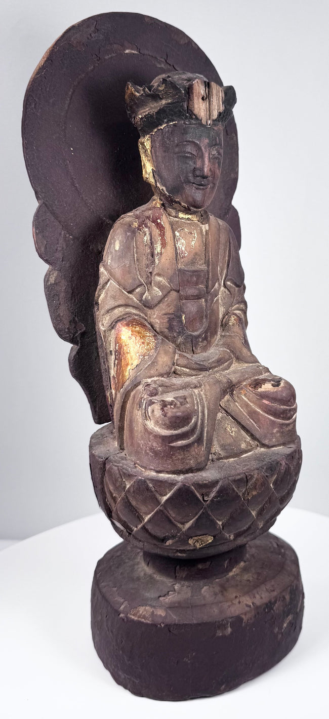 Aged circular wooden pedestal supporting the Guanyin statue with cinnabar-red pigment, cracks and historic surface losses