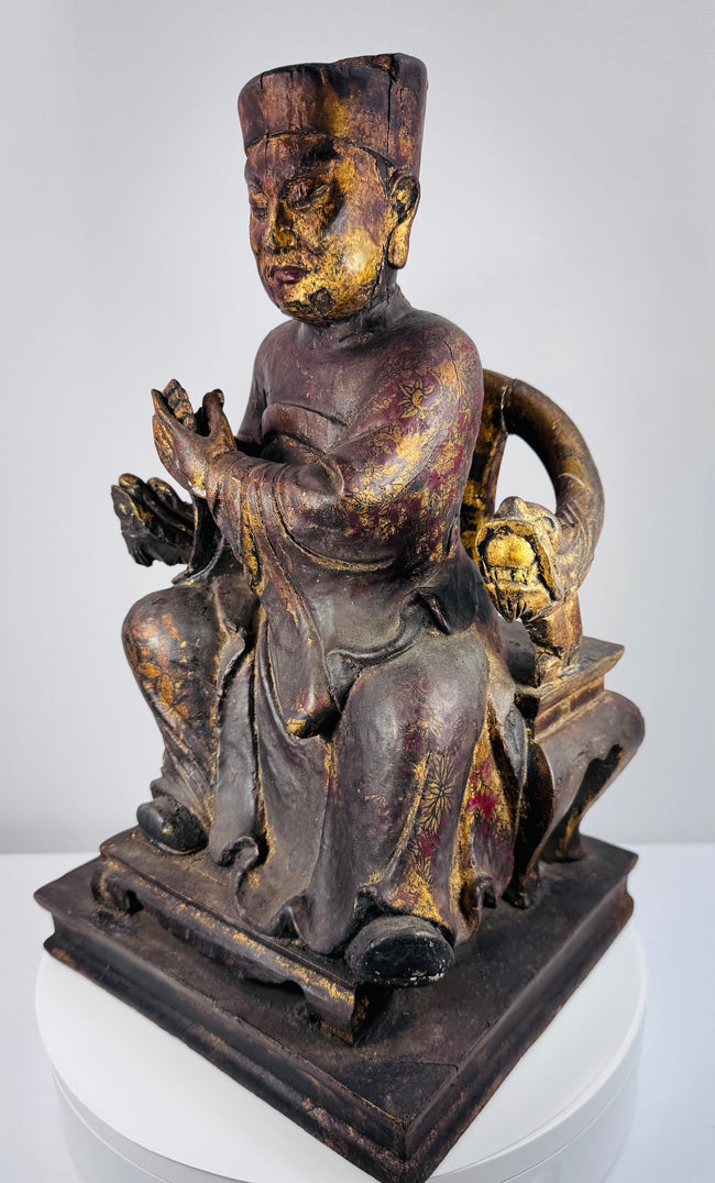 Angled view of Qing Dynasty carved wooden dignitary showing layered robes, throne arms and aged polychrome surface