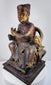 Angled view of Qing Dynasty carved wooden dignitary showing layered robes, throne arms and aged polychrome surface