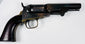 Antique Colt Model 1849 Pocket Revolver with an exposed hammer, worn steel cylinder, and warm-toned brass trigger guard.