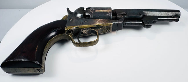 Colt Model 1849 Pocket Revolver highlighting the brass backstrap, rounded walnut grip base, and loading lever beneath the barrel.