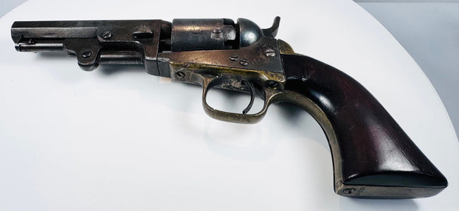 Colt Model 1849 Pocket Revolver showing dark steel patina, a brass trigger guard, and varnish on the walnut grip.