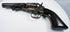 Colt Model 1849 Pocket Revolver showing dark steel patina, a brass trigger guard, and varnish on the walnut grip.