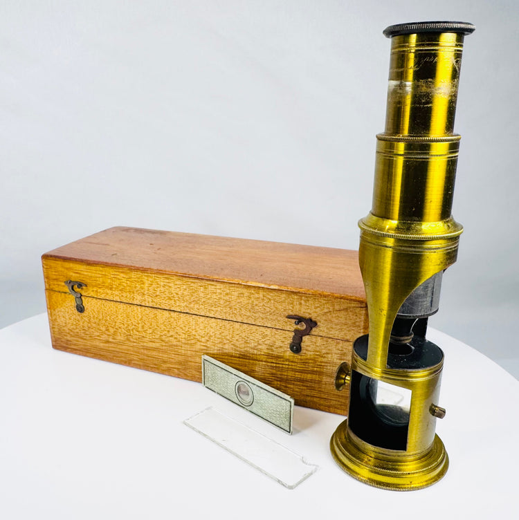 Historic brass optical microscope with mirror reflector and period microscope slides