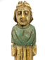 Close-up of antique European folk art wooden statue face with closed eyes and faded green paint