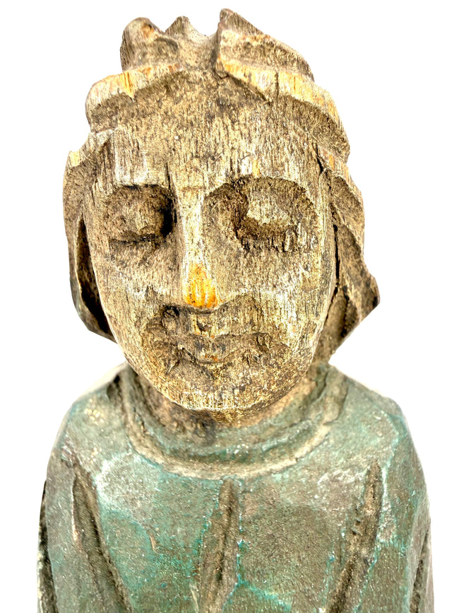 Close-up of antique carved wooden head with hollow eyes and distressed green shoulder paint