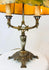 Museum-style display of a 1920s European Art Nouveau table lamp with painted parchment shade