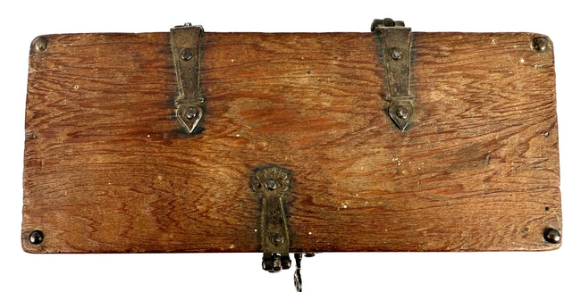 Bottom view of antique wooden strongbox displaying natural wood grain and four rounded iron foot studs
