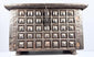 Long side of an antique Indian hardwood box showing rows of raised brass geometric panels and original fastening hardware.
