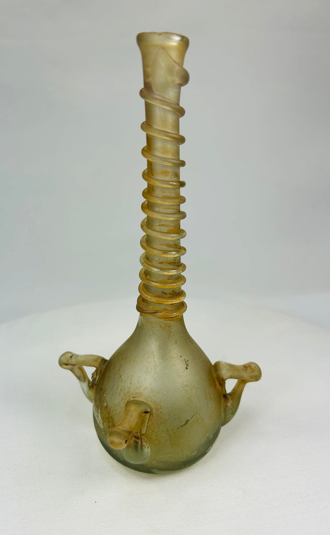 Oblique view of medieval Islamic glass vessel showing ribbed neck, bulbous body, and delicate iridescent surface.
