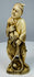 Rear three-quarter view showing the fisherman’s patterned garment and carved basket