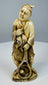 Front view of a Meiji–Taishō Japanese fisherman carving holding his catch