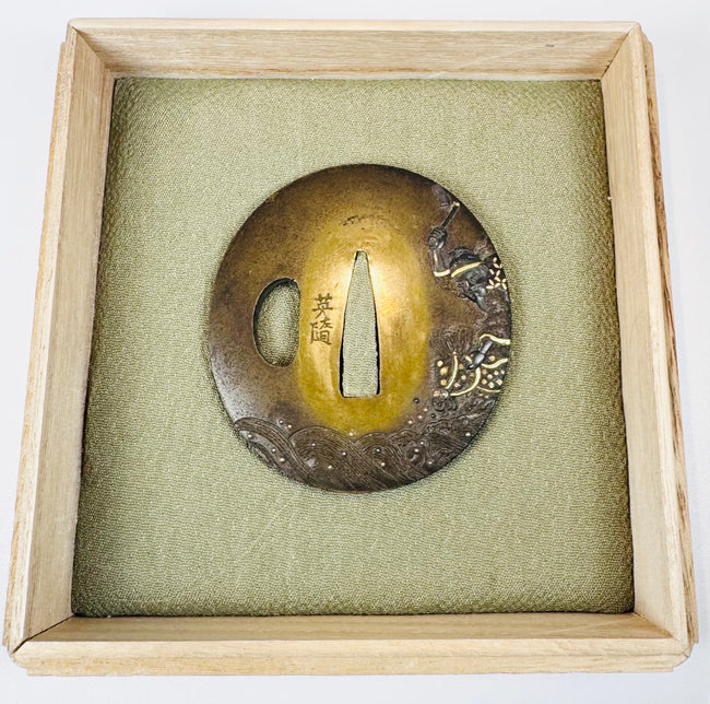 Late Edo Japanese mixed-metal tsuba with mounted warrior and horse relief displayed on green textile cushion