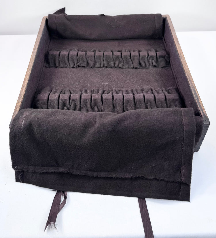 Close view of later fitted drawer insert showing dark anti-tarnish cloth, stitched loops and pull ribbons inside the ship chest