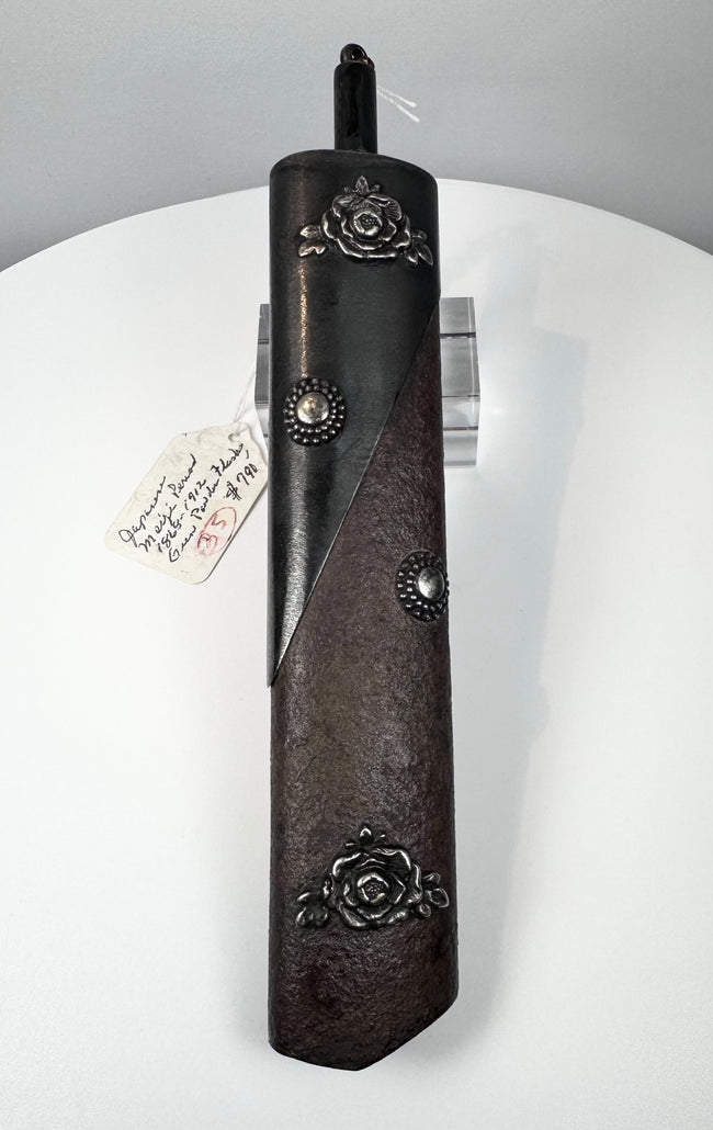 Angled view of Meiji period Japanese gunpowder flask showing dark patinated metal fittings and textured body