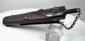 Angled rear view of antique Japanese gunpowder flask showing suspension clip, textured lacquered body and metal fittings