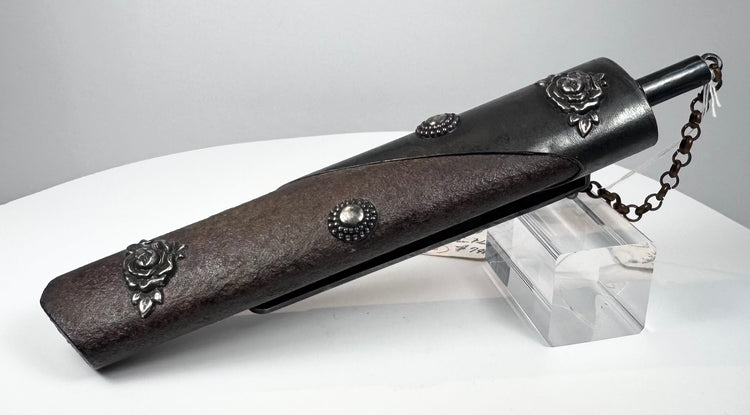 Antique Japanese Meiji period kayaku-ire gunpowder flask showing textured reddish-brown body, floral metal appliqués, beaded bosses, dispensing spout and securing chain