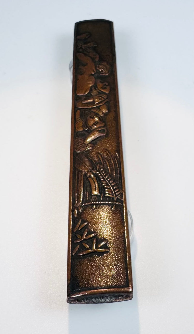Detailed view of the kozuka showing Zen figures, bamboo and landscape decoration