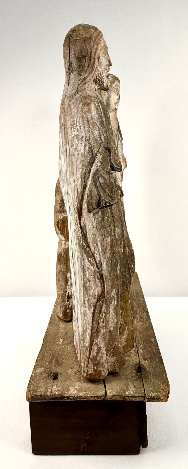 Side profile of antique carved wood Holy Family group highlighting vertical grain texture and plinth