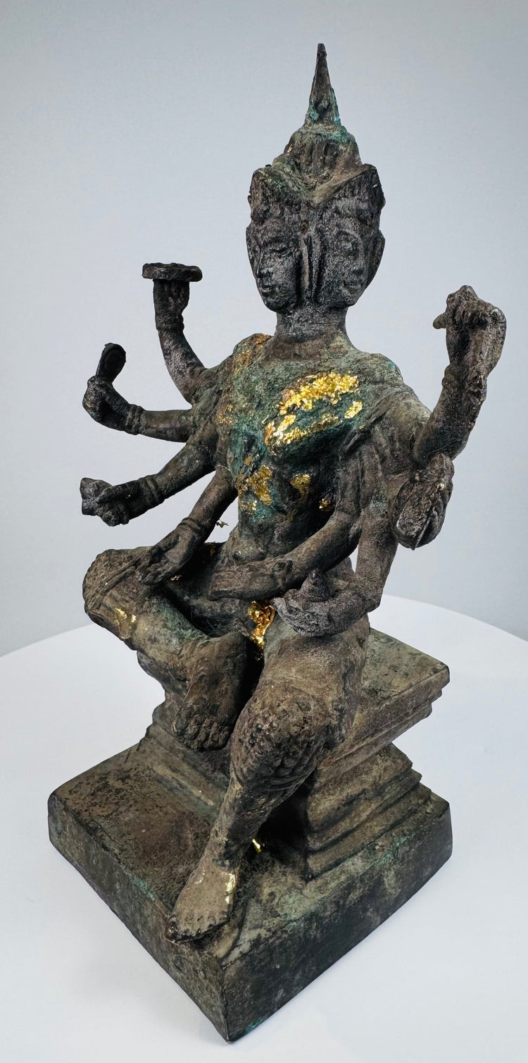 Angled view of Phra Phrom seated in royal ease upon a tiered pedestal
