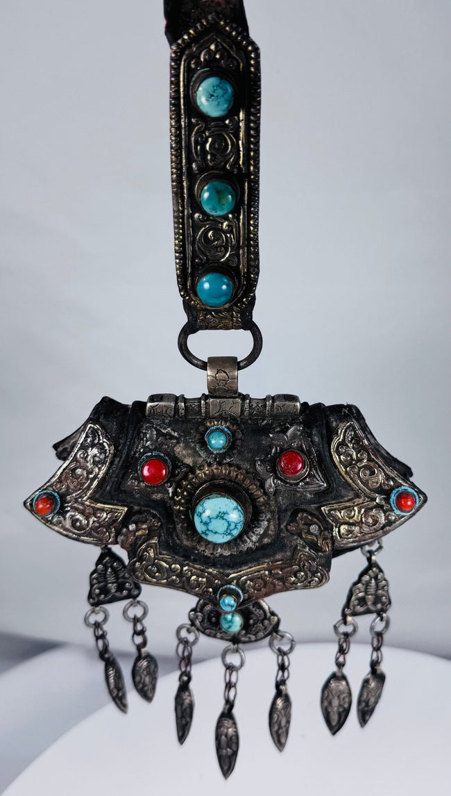 Late 19th century Tibetan ceremonial chest ornament with silvered metal, turquoise, coral, and hanging pendants.