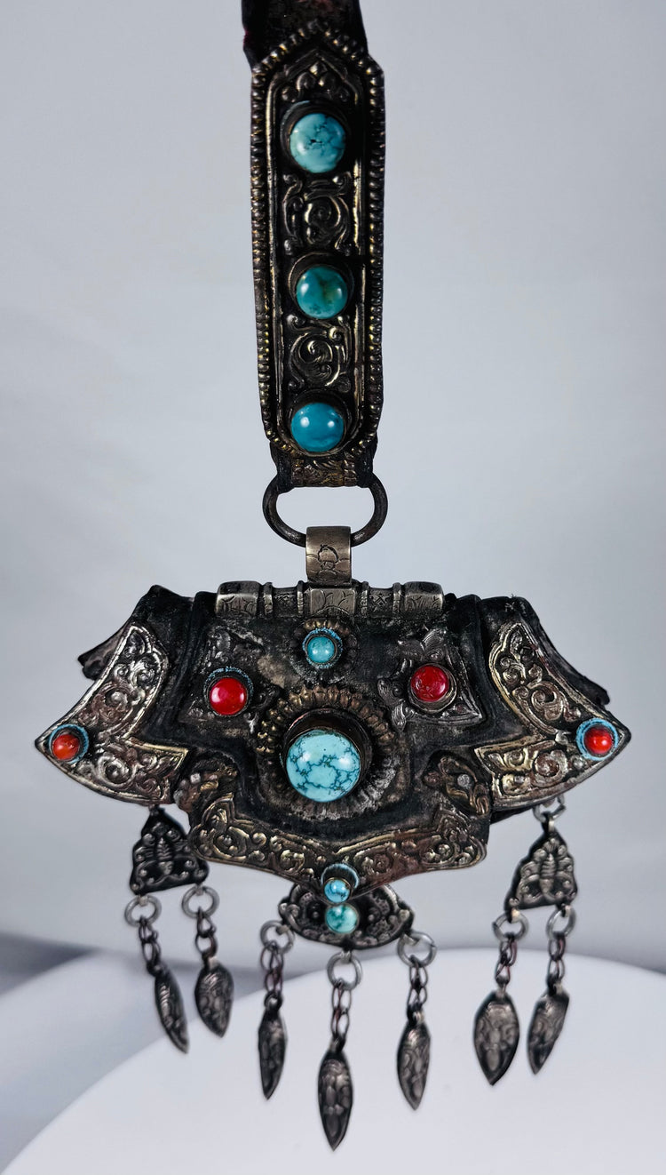 Late 19th century Tibetan ceremonial chest ornament with silvered metal, turquoise, coral, and hanging pendants.