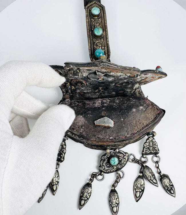 Traditional Tibetan devotional amulet container with repoussé decoration, turquoise settings, and ceremonial pendants.