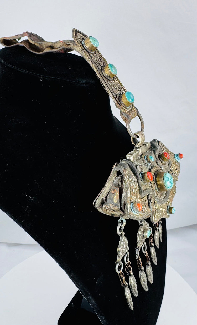 Antique Tibetan Buddhist gau amulet case displaying repoussé floral decoration and protective turquoise cabochons.