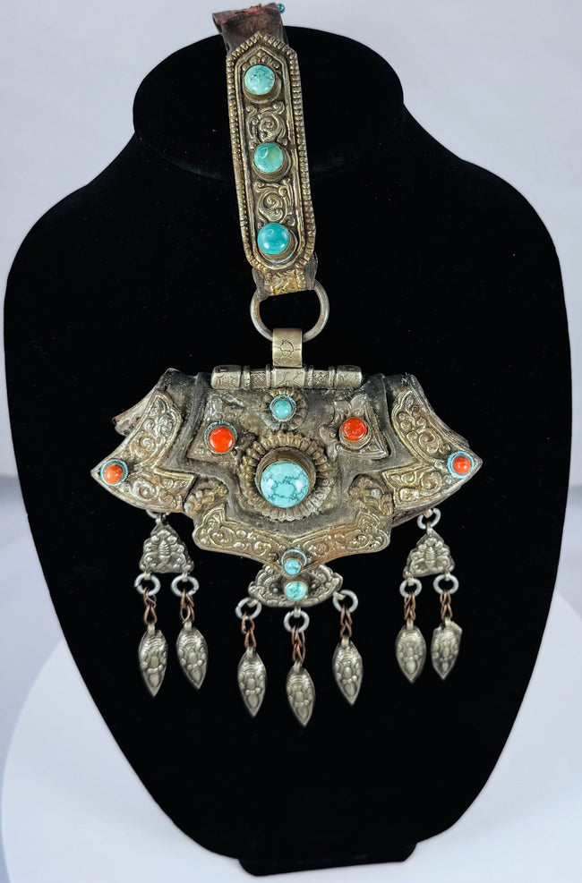 Traditional Himalayan gau amulet case featuring repoussé metalwork, turquoise inlay, and suspended pendant drops.