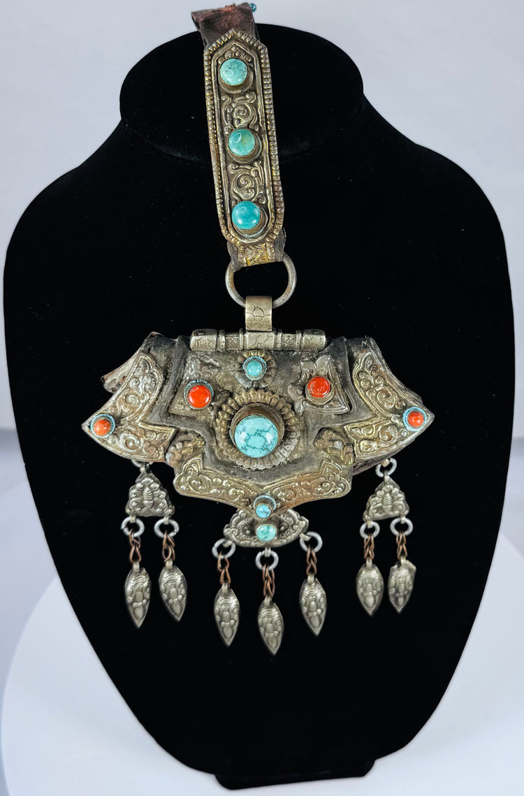 Traditional Himalayan gau amulet case featuring repoussé metalwork, turquoise inlay, and suspended pendant drops.