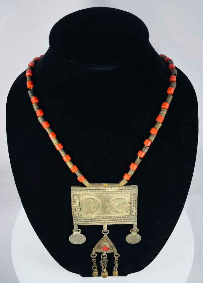 Historic Turkmen tribal necklace displaying traditional Central Asian jewelry with coin elements, red glass accents, and ornate metalwork.