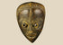 Antique Baule tribal mask from Ivory Coast, early 20th century, hand-carved wood with natural patina, oval face, almond-shaped eyes, and stylized features displayed on a stand.